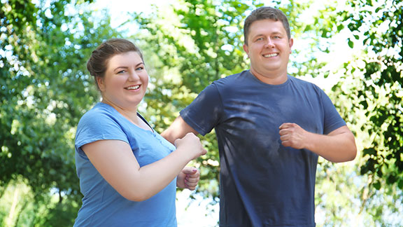 Female and male with obesity briskly walking.